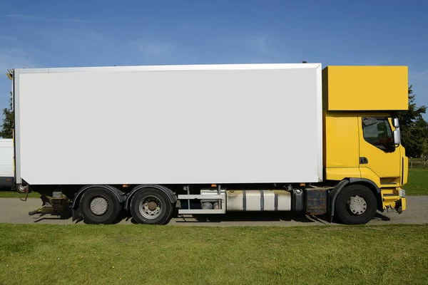 Large truck with yellow cabin and blank space on his side