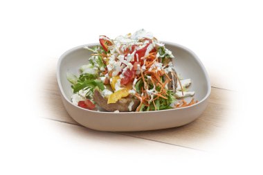 Sıcak patatesli kase, beyaz ve ahşap üzerine salata ve sebze.