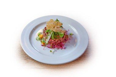 Beyaz tabakta beyaz tartar ve sığır eti var.