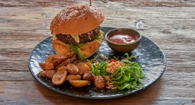 Biftek burgerli tabak ve ahşap masa üzerinde kızarmış patates.