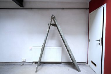 Dirty ladder in front on a white wall for renovation
