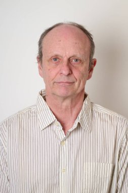 Beyaz duvara karşı pamuklu gömlekli yaşlı adam.