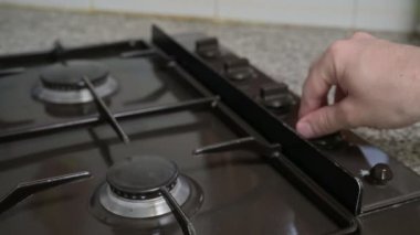 Erkeksi bir el mutfak ocağının gaz topuzunu kaldırır ve tepesine bir kahve ısıtıcısı koyar, alevin üzerine.