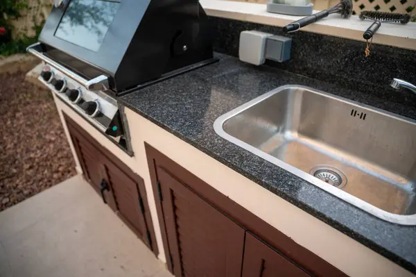 Evin bahçesinde mutfak lavabosuyla barbekü yapılmış.