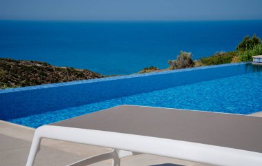 Beyaz güneş şezlongu, sahnenin en önemli parçasıydı. Davetiye havuzunun yanında mükemmel bir şekilde duruyordu. Yaz manzarası cennet gibiydi ve uzak deniz manzarası o anın sükunetini artırıyordu..