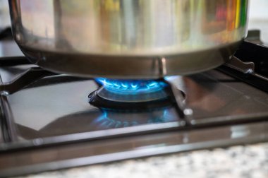 Mutfak gazının kapağı açık, tencereyi ısıtıyor..