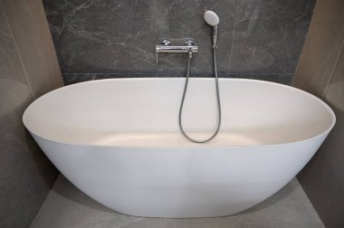 Minimalist banyo. Beyaz banyo küveti ve gümüş telefonlar duş alıyor.