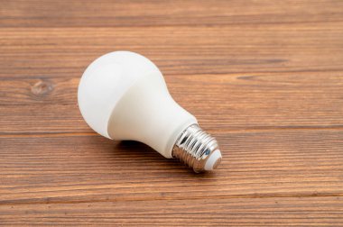 Bu, ahşap bir yüzey üzerinde duran bir LED ampulünün yakın plan görüntüsü.