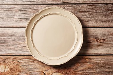 Tahta bir masanın üstündeki boş beyaz tabak.,            