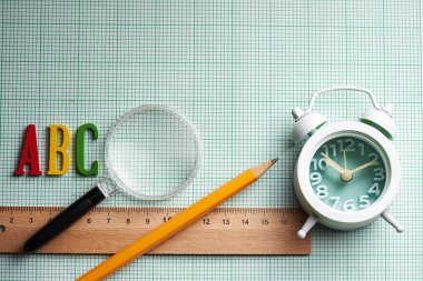cetvel kalem ve harf bir b c alarm saati ve grafik kağıdına büyüteç