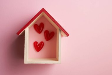 Kırmızı kalp küçük model bir evde şekilleniyor..