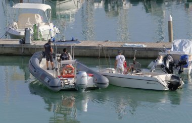 İtalya, Sicilya, Akdeniz, Marina di Ragusa (Ragusa Eyaleti); 28 Ekim 2022, limandaki motorlu teknelerde erkekler - EDITORIAL