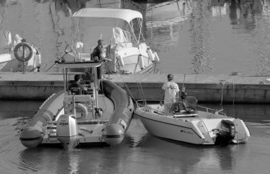 İtalya, Sicilya, Akdeniz, Marina di Ragusa (Ragusa Eyaleti); 28 Ekim 2022, limandaki motorlu teknelerde erkekler - EDITORIAL