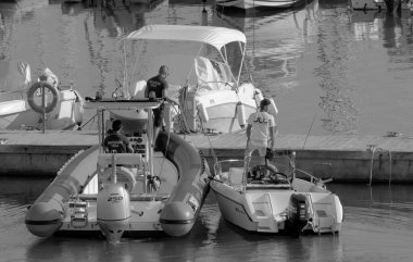 İtalya, Sicilya, Akdeniz, Marina di Ragusa (Ragusa Eyaleti); 28 Ekim 2022, limandaki motorlu teknelerde erkekler - EDITORIAL