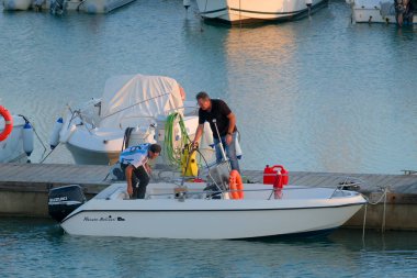 İtalya, Sicilya, Akdeniz, Marina di Ragusa (Ragusa Eyaleti); 3 Kasım 2022, gün batımında limanda insanlar, motorlu tekneler ve lüks yatlar - EDITORIAL