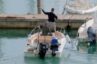 İtalya, Sicilya, Akdeniz, Marina di Ragusa (Ragusa Eyaleti); 11 Kasım 2022, limandaki bir motorlu teknede balıkçı - EDITORIAL