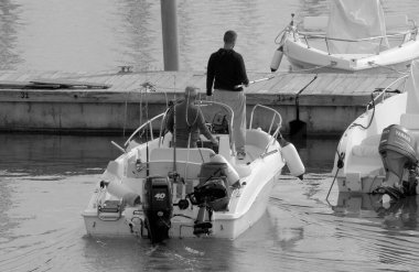 İtalya, Sicilya, Akdeniz, Marina di Ragusa (Ragusa Eyaleti); 11 Kasım 2022, limandaki bir motorlu teknede balıkçı - EDITORIAL