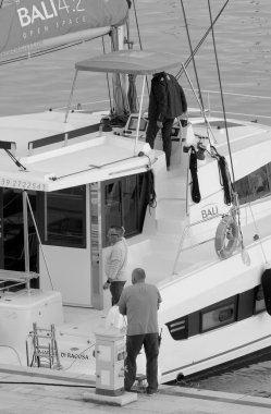 Taly, Sicilya, Akdeniz, Marina di Ragusa (Ragusa Eyaleti); 15 Kasım 2022, limandaki bir yelkenli teknesinde erkekler - EDITORIAL