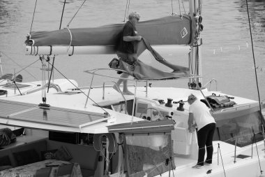 İtalya, Sicilya, Akdeniz, Marina di Ragusa (Ragusa ili); 6 Aralık 2022, limandaki bir yelkenli teknesinde çift - EDITORIAL