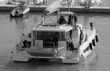 İtalya, Sicilya, Akdeniz, Marina di Ragusa (Ragusa Eyaleti); 15 Aralık 2022, limandaki bir katamaran yelkenli teknesi ve motorlu teknede insanlar - EDITORIAL