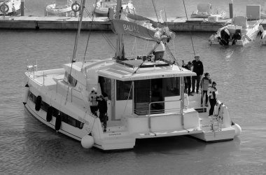 İtalya, Sicilya, Akdeniz, Marina di Ragusa (Ragusa Eyaleti); 17 Aralık 2022, katamaran yelkenli teknesi ve limandaki lüks yatlarda yaşayan insanlar - EDITORIAL