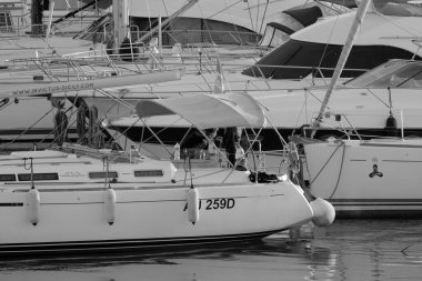 İtalya, Sicilya, Akdeniz, Marina di Ragusa (Ragusa Eyaleti); 30 Aralık 2022, limanda bir yelkenli teknesi ve lüks yatlarda bir çift - EDITORIAL