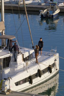 İtalya, Sicilya, Akdeniz, Marina di Ragusa (Ragusa Eyaleti); 2 Ocak 2023, limandaki katamaran yelkenli teknesinde insanlar - EDITORIAL