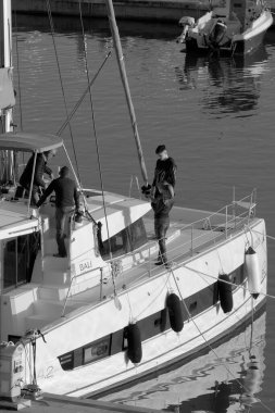 İtalya, Sicilya, Akdeniz, Marina di Ragusa (Ragusa Eyaleti); 2 Ocak 2023, limandaki katamaran yelkenli teknesinde insanlar - EDITORIAL