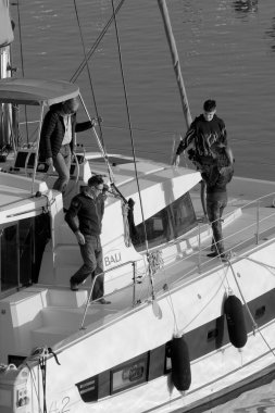 İtalya, Sicilya, Akdeniz, Marina di Ragusa (Ragusa Eyaleti); 2 Ocak 2023, limandaki katamaran yelkenli teknesinde insanlar - EDITORIAL