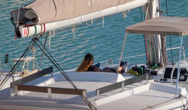 İtalya, Sicilya, Akdeniz, Marina di Ragusa (Ragusa Eyaleti); 4 Ocak 2023, limandaki bir yelkenli teknesinde kadın - EDITORIAL