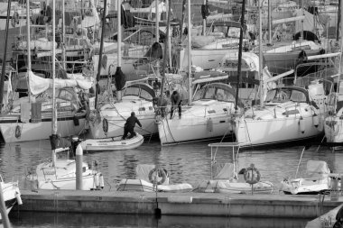 İtalya, Sicilya, Akdeniz, Marina di Ragusa (Ragusa Eyaleti); 6 Ocak 2023, limandaki bir yelkenli ve lüks yatlarda erkekler - EDITORIAL