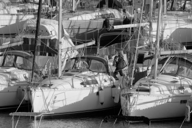 Italy, Sicily, Mediterranean sea, Marina di Ragusa (Ragusa Province); 21 February 2023, woman with a dog and sailing boats in the port - EDITORIAL