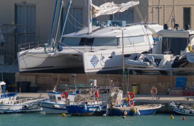 İtalya, Sicilya, Marina di Ragusa (Ragusa Eyaleti), 12 Mart 2023, limanda yerel balıkçı tekneleri ve lüks yatlar - EDITORIAL
