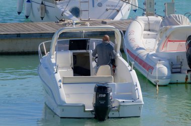 İtalya, Sicilya, Akdeniz, Marina di Ragusa (Ragusa Eyaleti); 17 Mart 2023, limandaki bir motorlu teknede adam - EDITORIAL