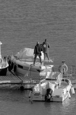 İtalya, Sicilya, Akdeniz, Marina di Ragusa (Ragusa Eyaleti), limanda lüks bir yatta yaşayan insanlar. 