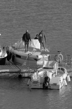 İtalya, Sicilya, Akdeniz, Marina di Ragusa (Ragusa Eyaleti); 25 Mart 2023, limanda lüks bir yatta insanlar - EDITORIAL