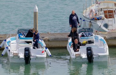 İtalya, Sicilya, Akdeniz, Marina di Ragusa (Ragusa ili); 7 Nisan 2023, limandaki motorlu teknelerde insanlar - EDITORIAL