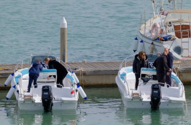 İtalya, Sicilya, Akdeniz, Marina di Ragusa (Ragusa ili); 7 Nisan 2023, limandaki motorlu teknelerde insanlar - EDITORIAL