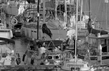 İtalya, Sicilya, Akdeniz, Marina di Ragusa (Ragusa Eyaleti); 4 Mayıs 2023, limandaki yelkenli teknelerinde erkekler - EDITORIAL