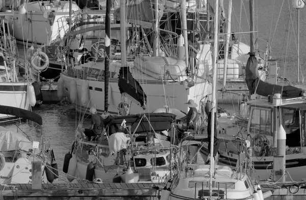 İtalya, Sicilya, Akdeniz, Marina di Ragusa (Ragusa Eyaleti); 4 Mayıs 2023, limandaki yelkenli teknelerinde erkekler - EDITORIAL