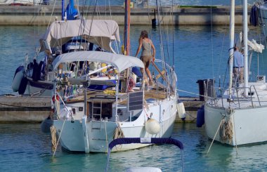 İtalya, Sicilya, Akdeniz, Marina di Ragusa (Ragusa Eyaleti), limandaki yelkenli teknesinde bir kadın 
