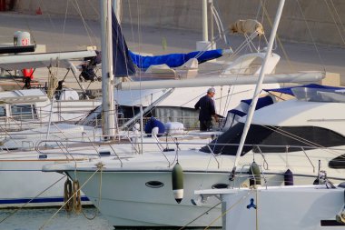 İtalya, Sicilya, Akdeniz, Marina di Ragusa (Ragusa Eyaleti), limanda bir yelkenli ve lüks yatlarda bir adam 