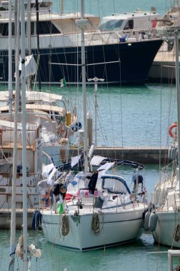 İtalya, Sicilya, Akdeniz, Marina di Ragusa (Ragusa Eyaleti); limandaki bir yelkenli teknesindeki insanlar 
