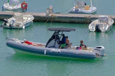 İtalya, Sicilya, Akdeniz, Marina di Ragusa (Ragusa Eyaleti); 3 Haziran 2023, limandaki kauçuk bir teknede insanlar - EDITORIAL