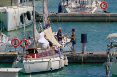 İtalya, Sicilya, Akdeniz, Marina di Ragusa (Ragusa ili); 10 Haziran 2023, limandaki insanlar ve yelkenliler - EDITORIAL