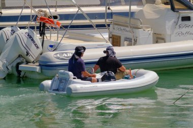 İtalya, Sicilya, Akdeniz, Marina di Ragusa (Ragusa ili); 10 Haziran 2023, limandaki küçük bir kauçuk teknede erkekler - EDITORIAL