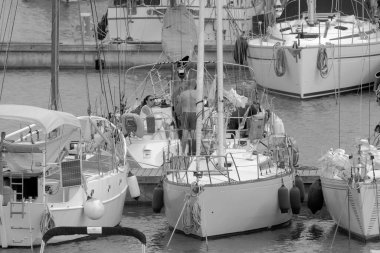 İtalya, Sicilya, Akdeniz, Marina di Ragusa (Ragusa ili); 10 Haziran 2023, limandaki bir yelkenli teknesinde insanlar - EDITORIAL