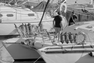 İtalya, Sicilya, Akdeniz, Marina di Ragusa (Ragusa ili); 11 Haziran 2023, limandaki bir yelkenli teknesinde insanlar - EDITORIAL