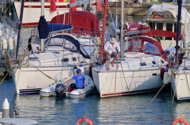 İtalya, Sicilya, Akdeniz, Marina di Ragusa (Ragusa ili); 18 Haziran 2023, limandaki bir yelkenli teknesinde erkekler - EDITORIAL