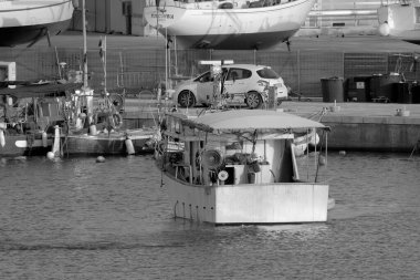 İtalya, Sicilya, Marina di Ragusa (Ragusa Eyaleti); limandaki ahşap bir balıkçı teknesinde balıkçı. 